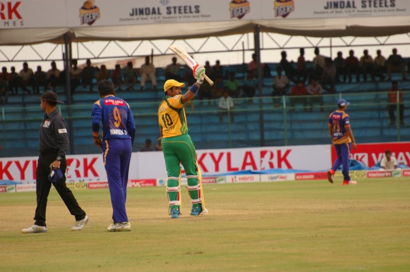 Robin Uthappa raises his bat towards his team dug-out after completing his half century